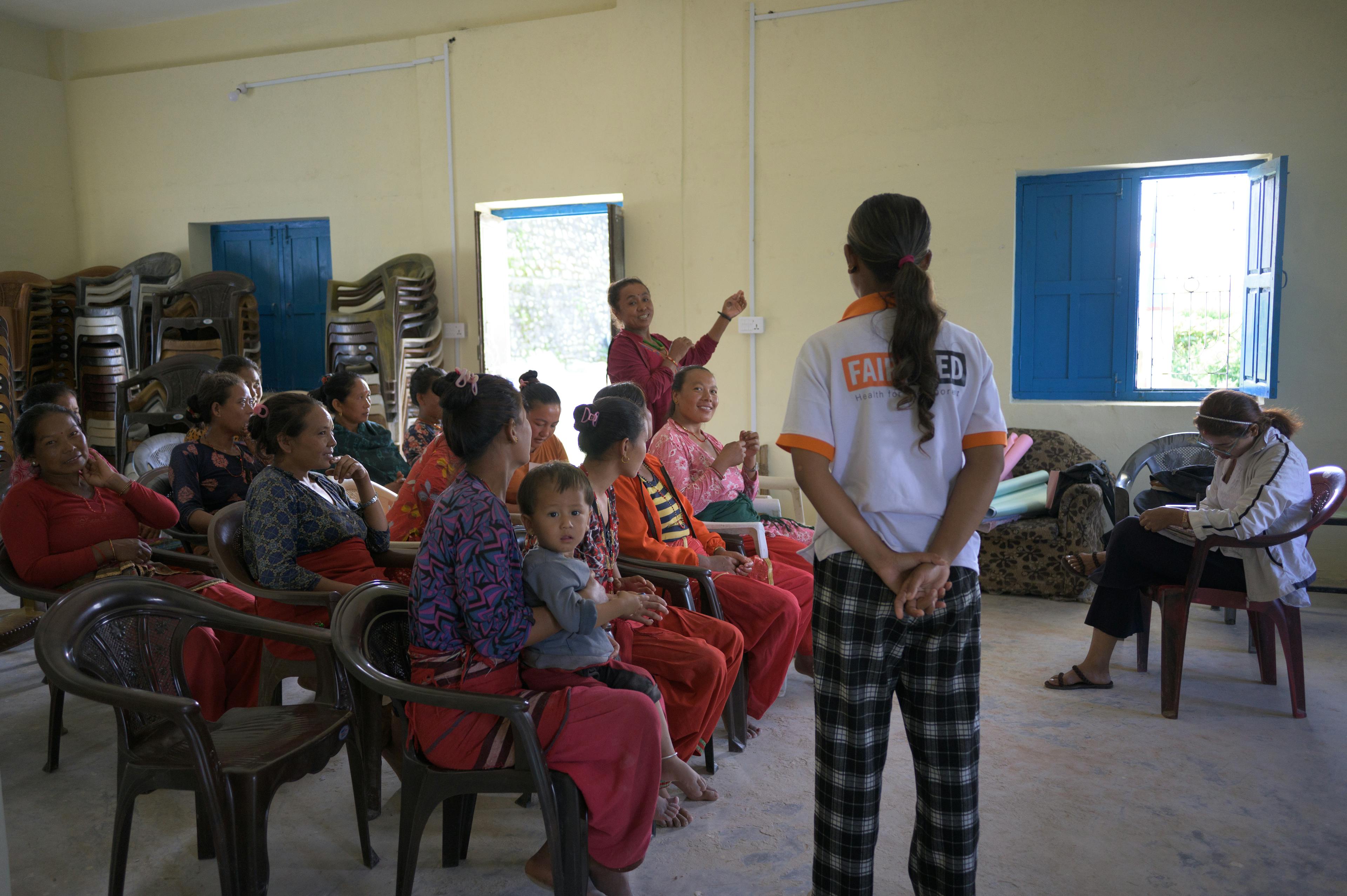Sujita se tient devant un groupe de mères composé de 13 mères et d'un enfant et écoute la question d'une mère.