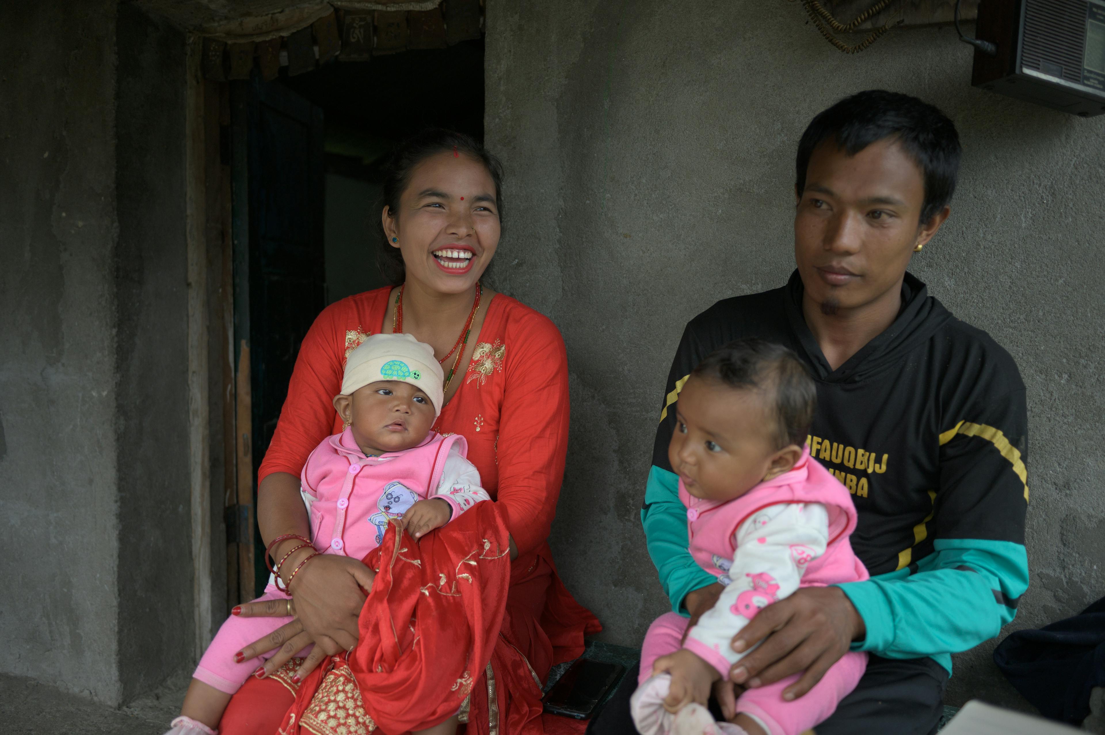 Nani Ram Tamang et Priya Tamgang sont assises sur un banc devant leur maison avec leurs jumeaux.